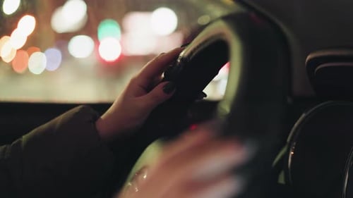 Woman driving car at night in city