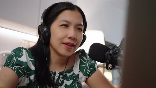 Woman Talks into Microphone Wearing Headphones Indoors