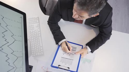 Business Man Filling Out Charts in Office