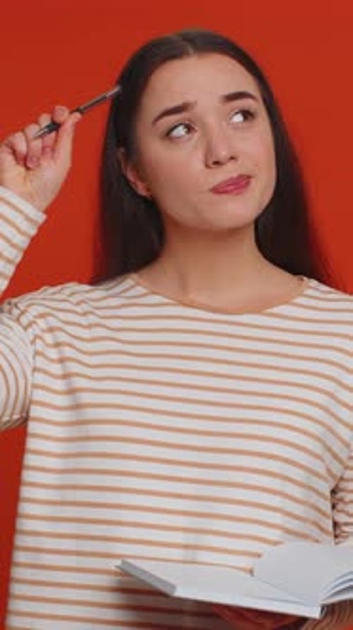 Woman with Notebook Thinks, Writes, and Smiles