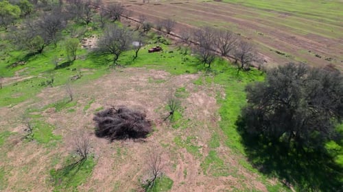 Aerial flight over an abandoned in a ranch. Camera flies over a sparsely vegetated field with the ab