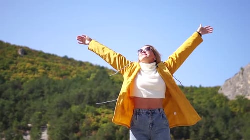 Blonde Woman Outdoors with Arms Raised