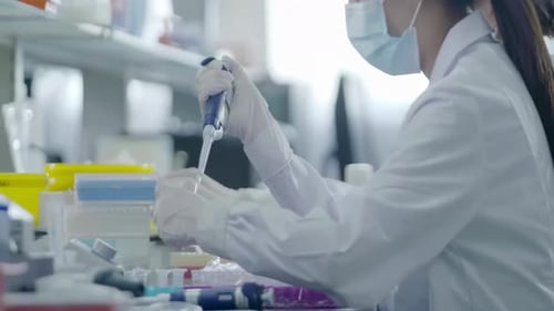 Female Scientist Using Pipette in Bright Lab