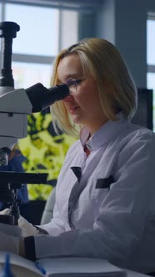 Woman Scientist Examining Sample Under Microscope in Lab