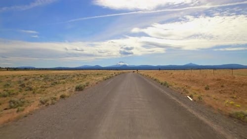 Oregon road winds through mountain landscape under summer blue sky