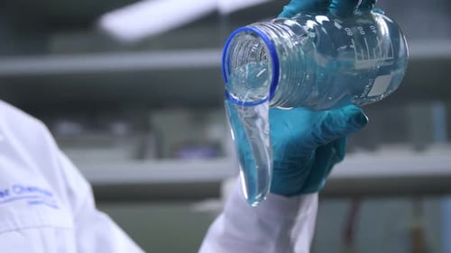 Scientist Pours Clear Liquid from Glass Beaker