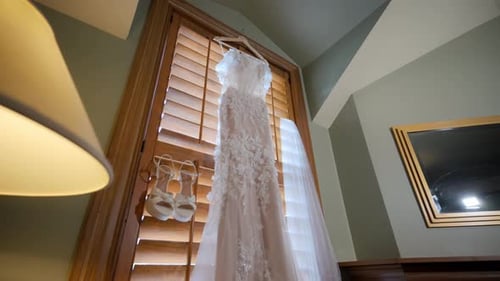 Wedding Dresses Bridal Veil and Shoes are Hanging Near the Window Wide View