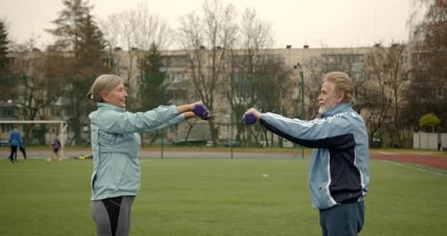 Couple of Senior People Exercise Outdoors on a Stadium