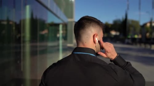 Man Walking with Earbuds in Urban Setting