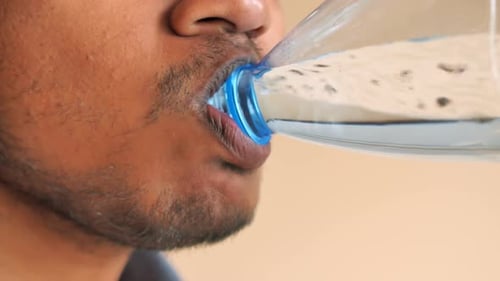 Young Men Drinking Water From a Plastic Water Bottle