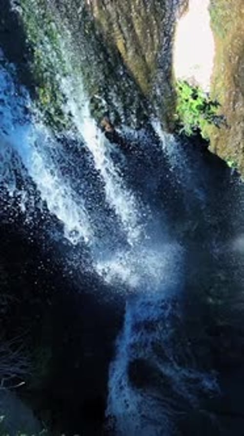 Experience the Breathtaking Beauty of a Waterfall Cascading Through a Stunning Rock Formation