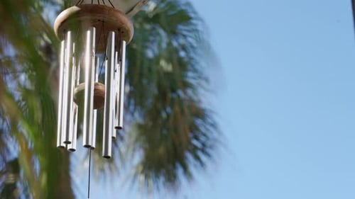 Calming and relaxing view of a wind chime with some palm trees in the background, in a nice, tropica