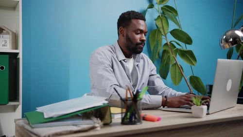 A Focused Professional Individual Working Diligently on a Laptop in a Modern Office Environment