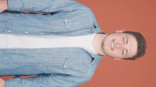 Smiling Man in Denim Shirt on Solid Background