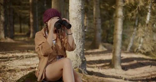 Female Tourist Searching Through Binoculars in Forest