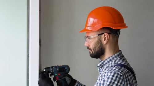 Man in Uniform Does Pvc Window Installation with a Screwdriver in Office or Apartment
