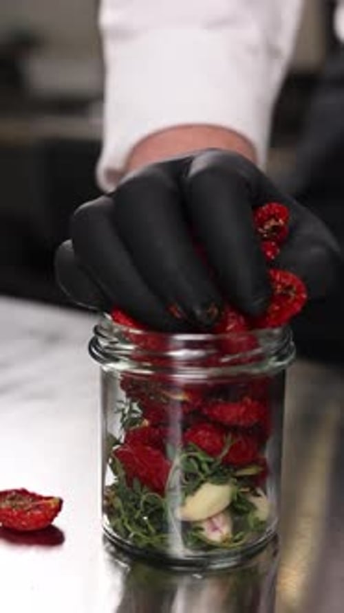 The chef preserves vegetables in the kitchen. Close-up