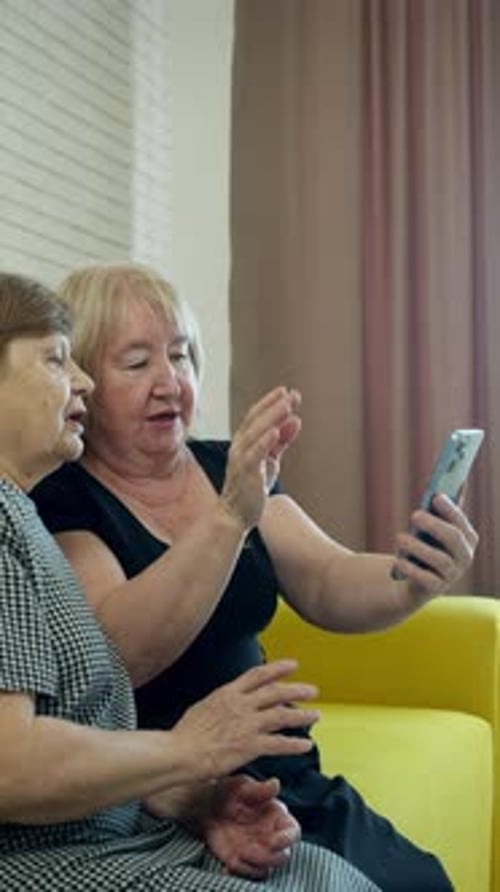 Senior Women Using Mobile Phone Together Indoors