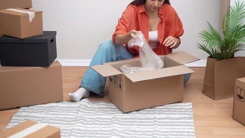 Woman Unpacking Lamp from Moving Box on Floor