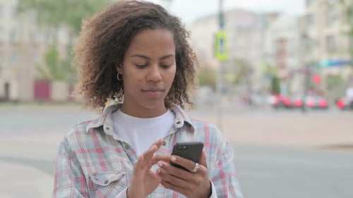 Young Woman Using Smartphone on Urban Street