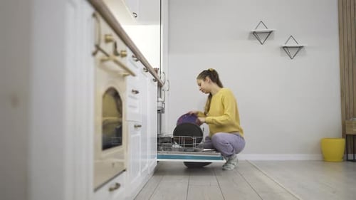 Woman Loading Dishes into Dishwasher During Home Kitchen Chores and Spring Cleaning