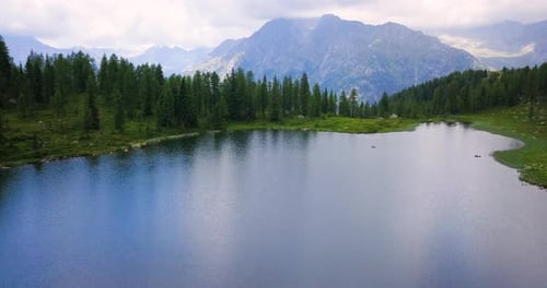 Aerial image of a lake surrounded by nature among trees and mountains.