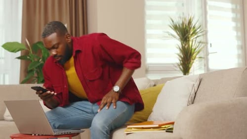 Attractive Young African American Businessman Talking on Phone Use Laptop Working From Home Office