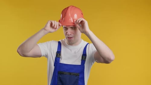 Happy Positive Mature 30s Worker Builder Man Dancing in Helmet on Yellow Studio