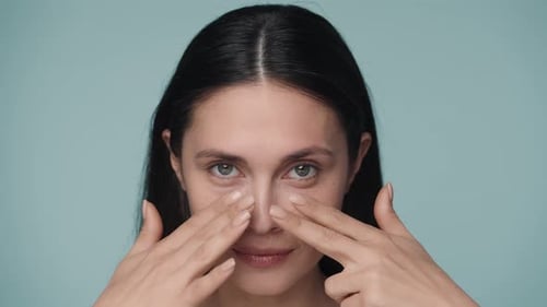 Young Adult Caucasian Woman Runs the Fingers of Both Hands Under Her Eyes Close Up of a Woman's Face