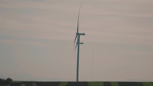 Slow motion shot of a wind turbine in a field during sunset