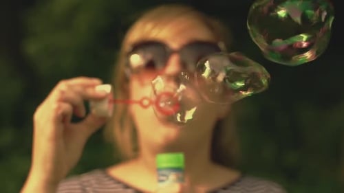 Woman blowing bubbles in park on sunny day