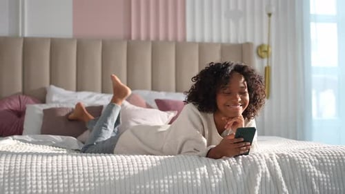 African Girl Holding Smartphone Touch Screen Typing Scroll Page at Home Woman with Cell Phone