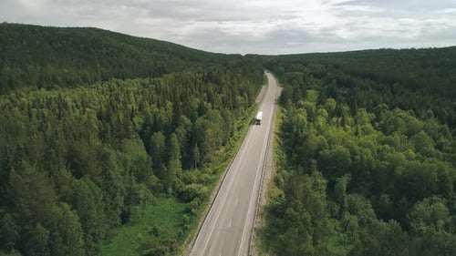 Aerial View of an Intercity Highway with Traffic Going Through a Green Forest on Bright Sunny Day