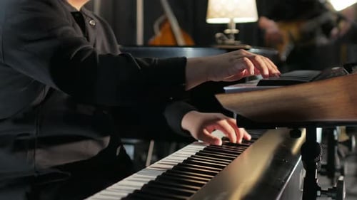 Hombre de traje tocando dos teclados con banda