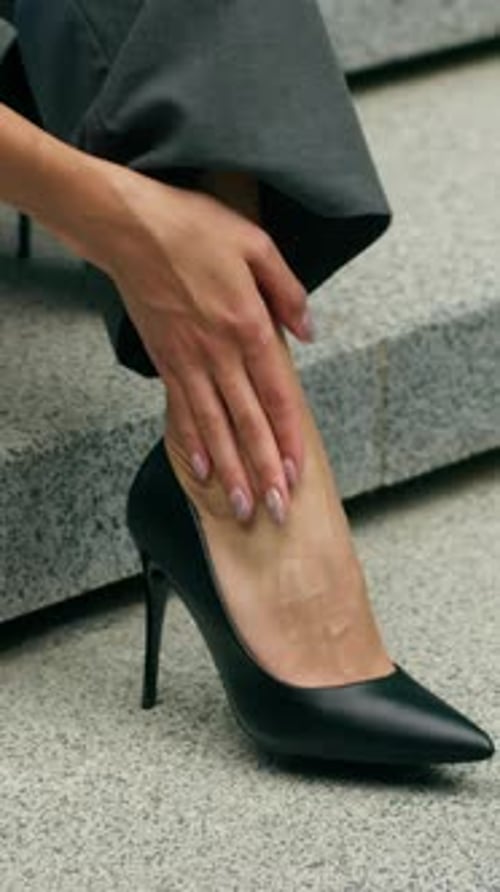 Woman Sitting on Stairs Holding Foot in Pain