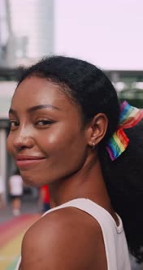 Vertical clip. A young black woman shows off her homosexual identity in a pride parade.