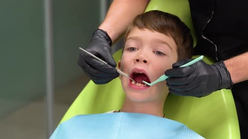 Closeup of Little Boy Opening His Mouth Wide During Treating Teeth By the Dentist