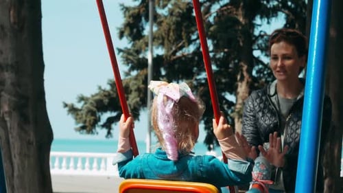 Mama schwingt kleines Mädchen auf Schaukel