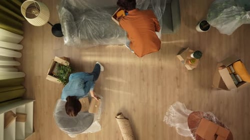 Top View Living Room Couple Man and Woman Unpacking Boxes with Stuff and Furniture in Film in New