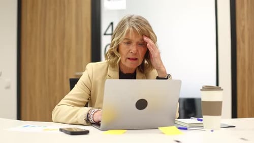 Gestresste ältere Geschäftsfrau leidet unter Kopfschmerzen bei der Arbeit