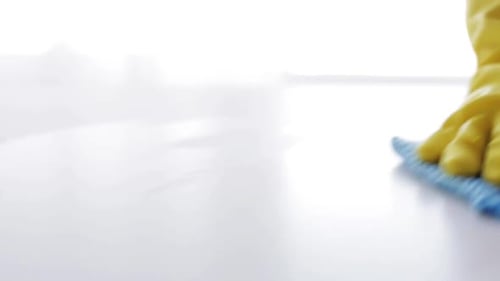 Cleaning White Surface With Wipe and Yellow Gloves