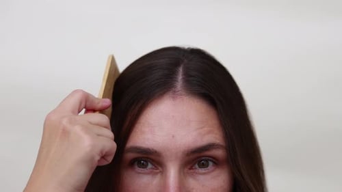 Woman Parts Her Hair with a Comb