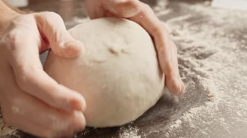 Hands Kneading Dough on Floured Surface
