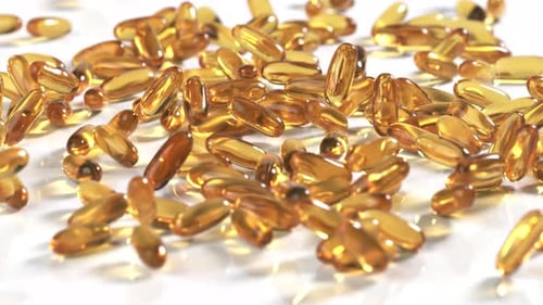 Golden Capsules Falling on White Surface