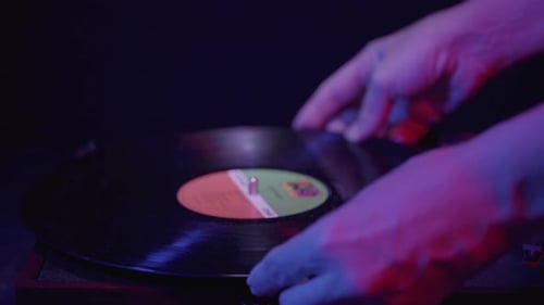 Hands Place Record on Turntable in Blue Light