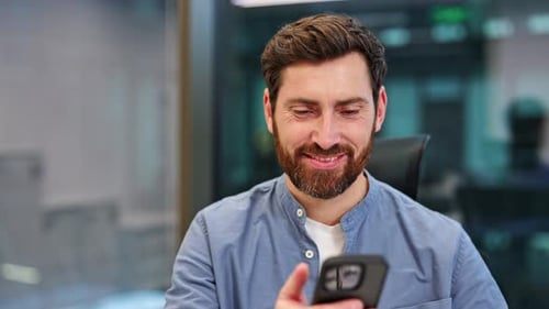 Happy Businessman Using Smartphone in Modern Office