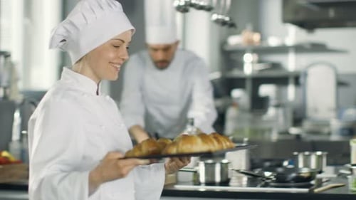 Smiling Woman Holding Tray of Croissants in Kitchen