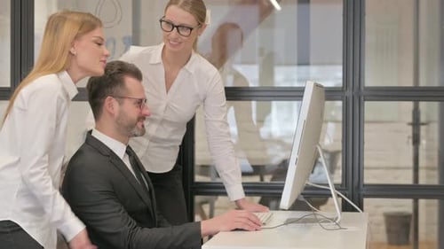 Business Team Collaborating on Computer in Office