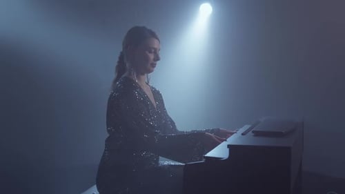 Elegant Woman Plays Piano Under Spotlight in Dark Room
