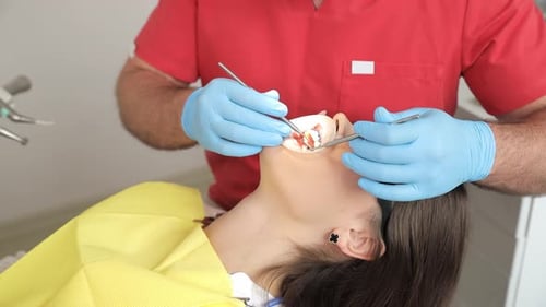 Dentist Examining Patient's Teeth with Dental Instruments